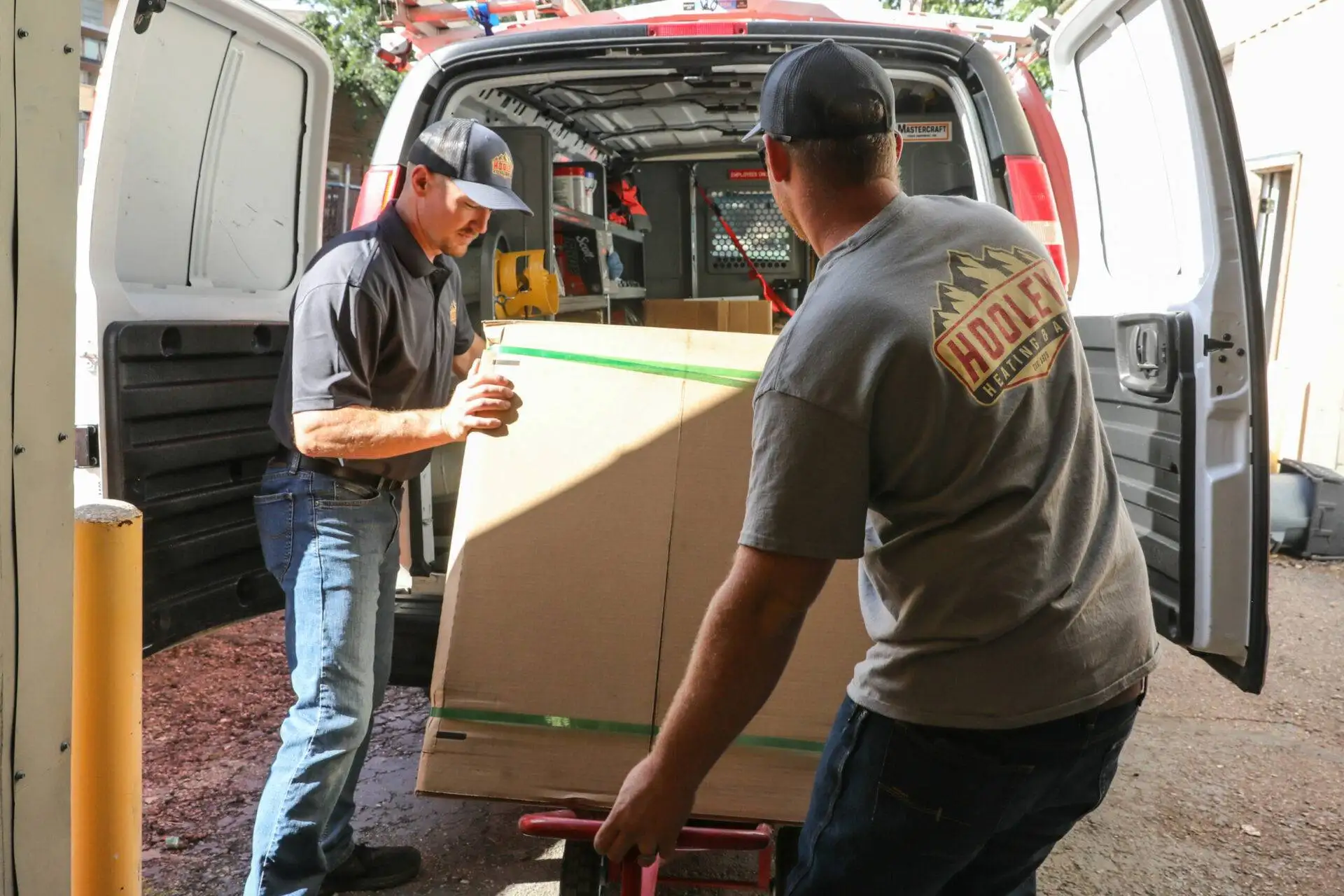 Image of Holley Heating & Air technicians loading a heat pump unit for installation for a Fort Collins customer