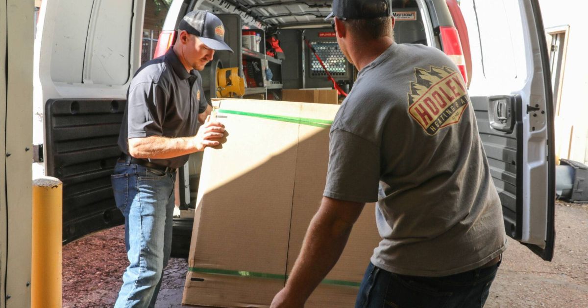 Image of Holley Heating & Air technicians loading a heat pump unit for installation for a Fort Collins customer
